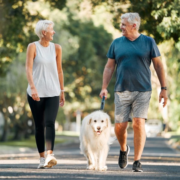 Older couple discuss compounding for pets while on walk with white haired dog