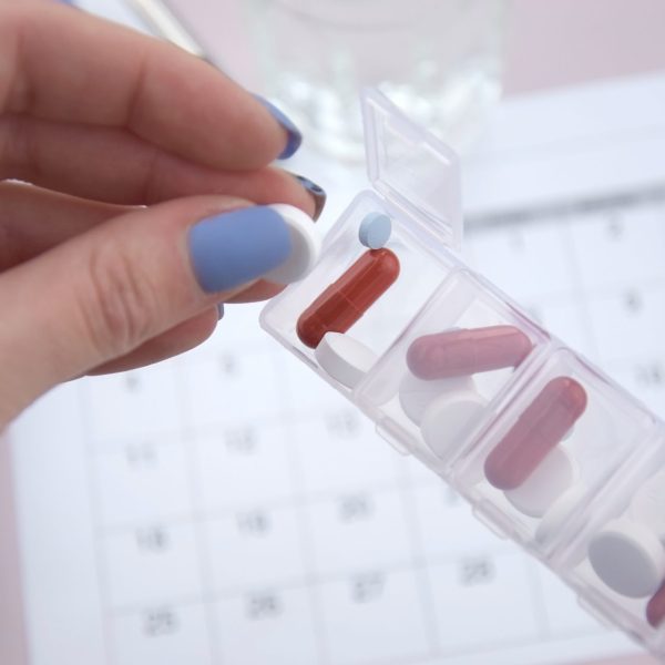 Woman taking medicine out of a weekly pill container
