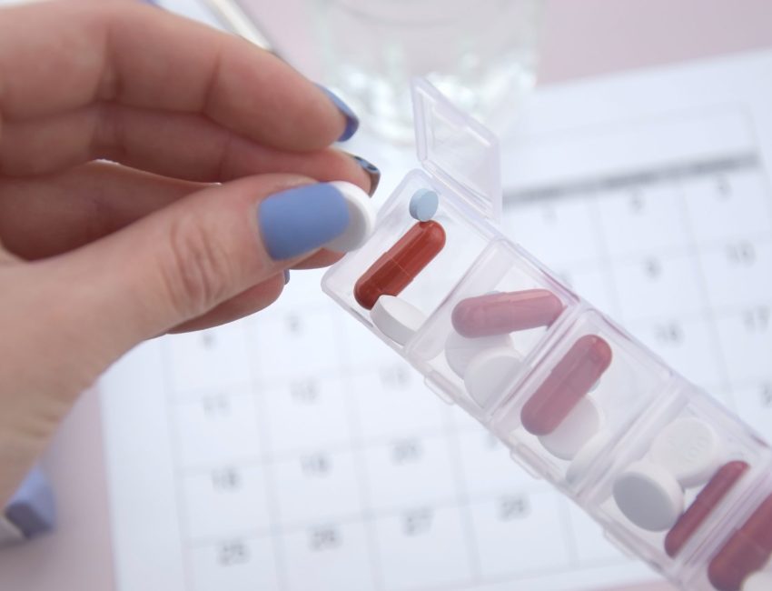 Woman taking medicine out of a weekly pill container