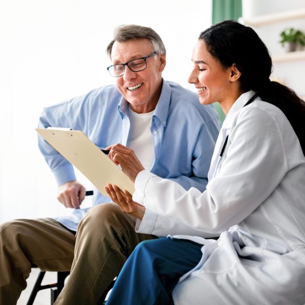 Older man talks with pharmacist about Medicare open enrollment