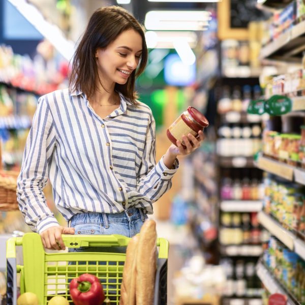 Woman reads the nutrition label on a jar of at store