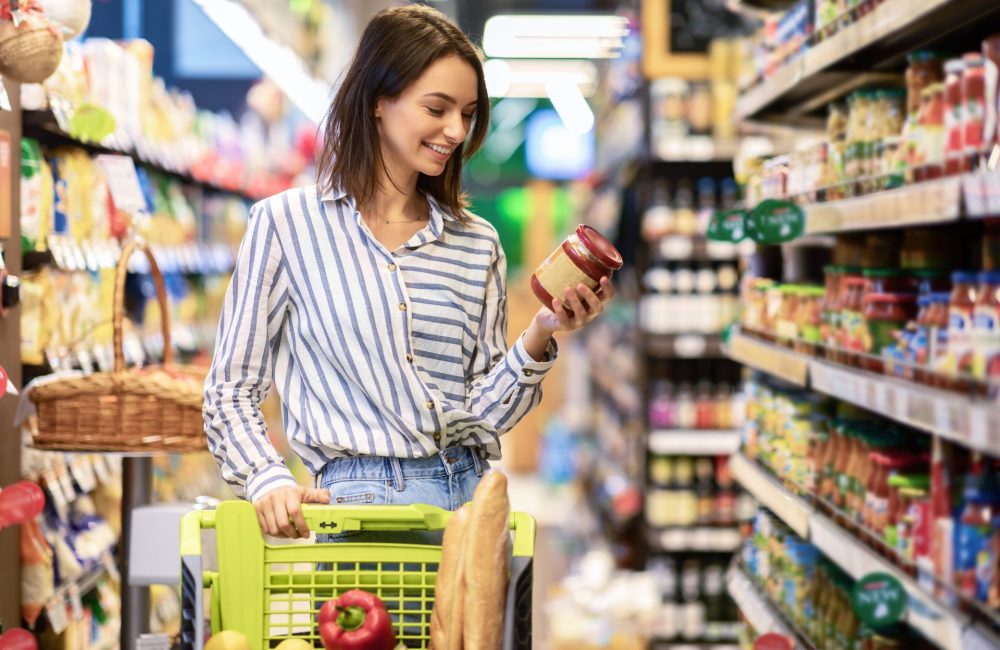 Woman reads the nutrition label on a jar of at store